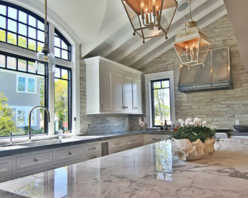 Kitchen design with marble counter and vaulted picture windows